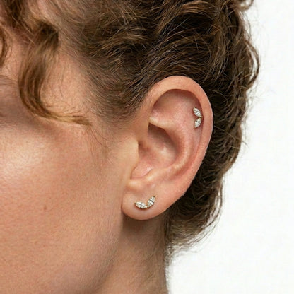 Close-up of an ear with multiple marquise cubic zirconia earrings on a white background